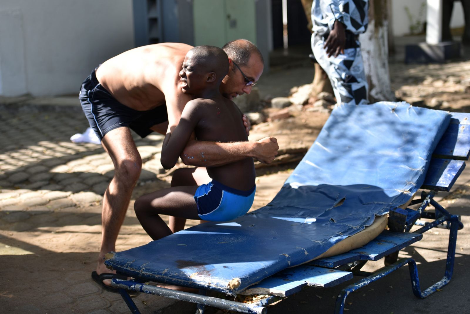 A man helps a wounded child after heavily armed gunmen opened fire on March 13, 2016 at a hotel in the Ivory Coast beach resort of Grand-Bassam. At least five people were killed on March 13 when heavily-armed gunmen opened fire in the Ivory Coast resort town of Grand-Bassam, leaving bodies strewn on the beach. "At the moment there are five dead," a military source said on condition of anonymity after the assault in the resort popular with Westerners. AFP,  SIA-KAMBOU
